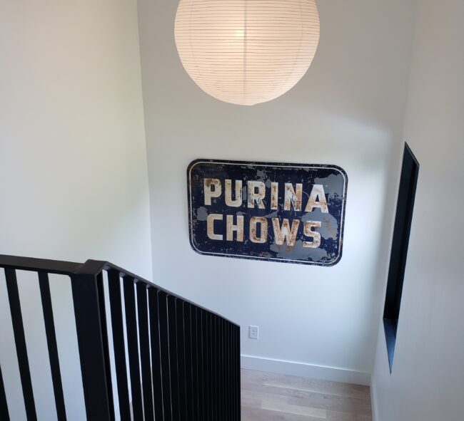 Modern wood staircase with black metal handrails leading down to a landing