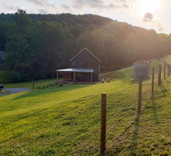 Modern farmhouse home sitting on a green hill at sunset in the country